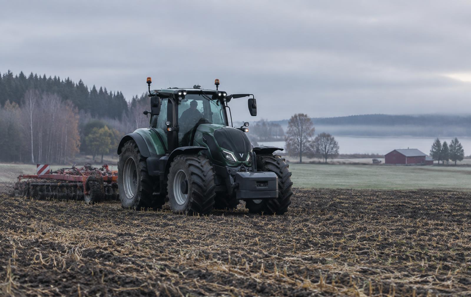 Traktor med harv på en åker en dimmig höstmorgon