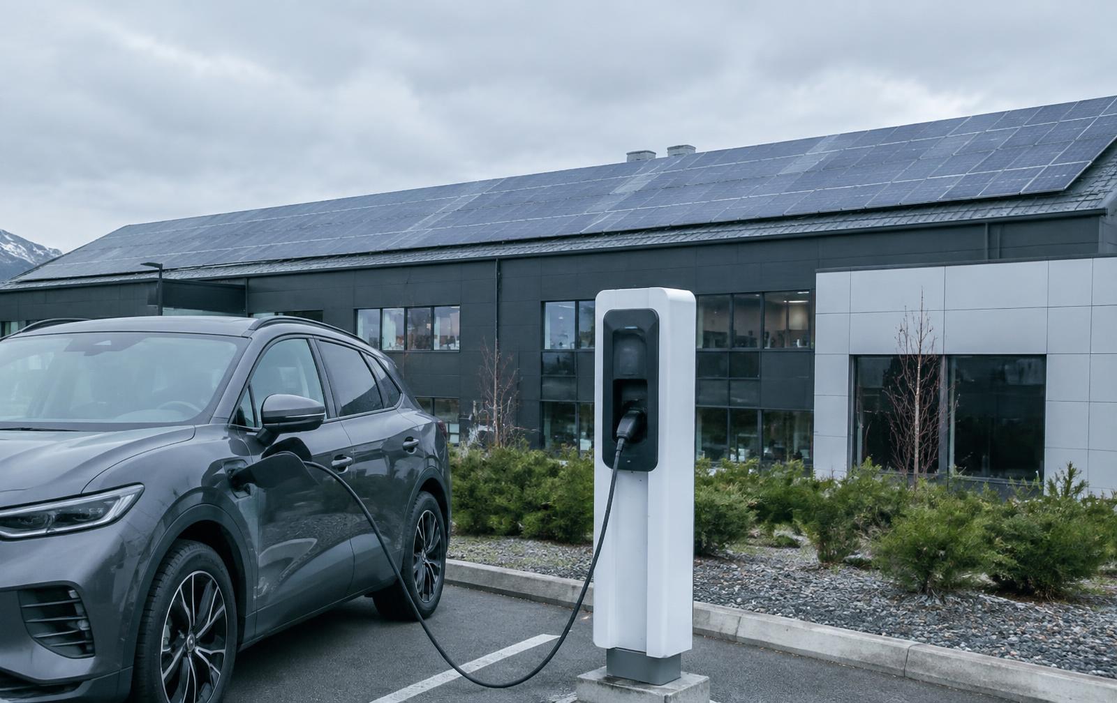 Solceller på en företagsfastighet med laddstolpe på parkeringen